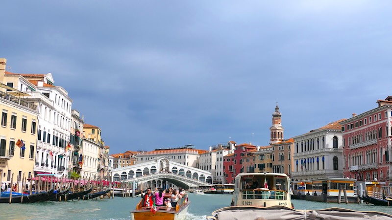 venedig-canale-grande-mit-rialtobruecke-vom-wassertaxi-aus Der Canale Grande mit der Rialtobrücke in der Mitte, fotografiert aus einem Wassertaxi. Im Vordergrund ist links das H10 Hotel zu sehen.