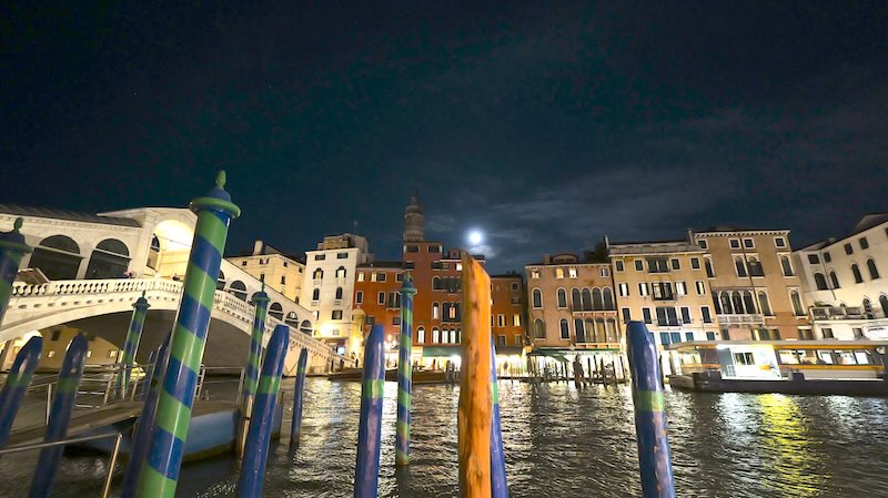 venedig-rialtobruecke-bei-nacht Die Rialtobrücke in Venedig bei Nacht. Im Vordergrund sind die gestreiften Markierungstäbe zu sehen.