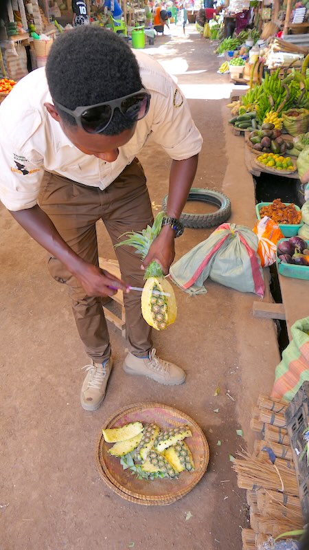 tansania-lake-manyara-mto-wa-mbu-markt-12 Elly bereitet eine Ananas verzehrfertig zu.
